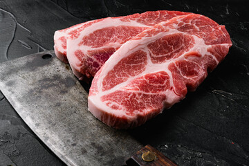 Wall Mural - Fresh steaks from Raw pork meat, and old butcher cleaver knife, on black dark stone table background