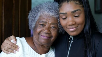 Wall Mural - A teen granddaughter embracing grandmother a black girl embraces grandparent