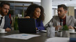 © stockbusters - Multiracial coworkers talking finance using laptop in modern company office.