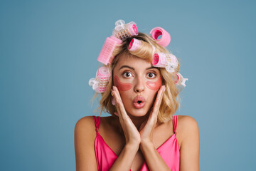 Wall Mural - Young woman with curlers and eye patches expressing surprise