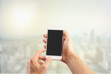 Canvas Print - Human hand holding phone with blank screen and cityscape blur background