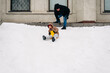 © ADDICTIVE STOCK - Father pushing kid on snow saucer riding down hill