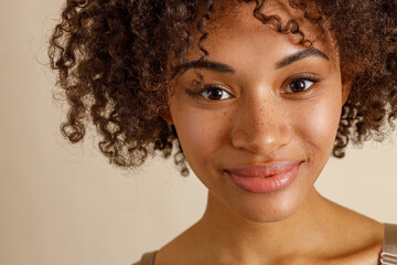 Wall Mural - Beautiful lady with curly hairstyle posing against beige wall