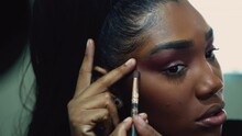 A black girl applying make-up preparing to go out