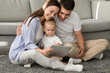 © Prostock-studio - Cute Infant Boy Using Digital Tablet While Relaxing With Parents At Home