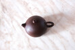 © Olga Panova - A teapot made of brown clay on a marble countertop before a tea party, top view