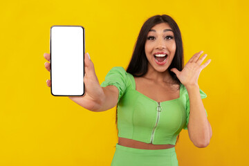 Excited woman showing white empty smartphone screen in hand