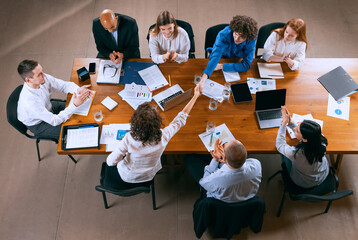 Wall Mural - Aerial view of young multiethnic people talking, working with colleagues, co-workers at office, indoors. Work, finance, tech concept.