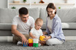 © Prostock-studio - Mom And Dad Spending Time With Infant Kid, Playing Building Blocks Together