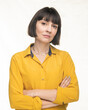 American woman with short brown hair poses in studio in a yellow shirt.