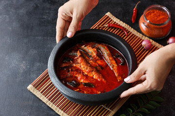 Canvas Print - Sardine fish curry hot spicy Kerala masala fish curry rice India woman hand serving Indian food red chili curry leaf Asian cuisine Bengali Goan red fish curry coconut milk mango clay pot Sri Lanka