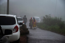 Stock Photo Of A White Color Parked On The Side Of The Road, Few People Moving Forward. Picture Captured During Monsoon Season Under Foggy Climate At Sateri Hills Station , Kolhapur, Maharashtra.