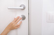 Cleaning door handles with an antiseptic wet wipe and gloves. Sanitize surfaces prevention in hospital and public spaces against corona virus. Woman hand using towel for cleaning home room door link.