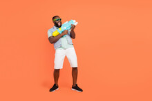 Photo Of Funky Guy Dressed Jeans Waistcoat Dark Glasses Shooting Water Gun Empty Space Isolated Orange Color Background