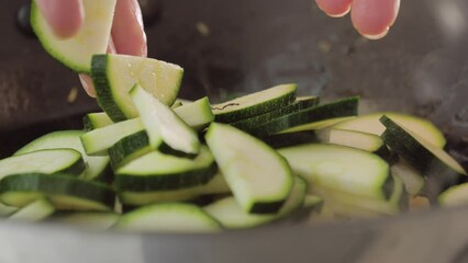 Wall Mural - cooking vegetable, zucchini slices falling down in a pan. Food footage, preparing dinner, healthy lunch. season with vegetable nut.