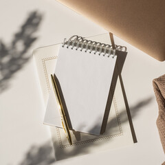 Wall Mural - Blank paper sheet notebook with copy space, flower sunlight shadows and laptop computer on white background. Aesthetic luxury minimalist workspace. Flat lay, top view