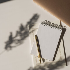 Wall Mural - Blank paper sheet notebook with copy space, flower sunlight shadows and laptop computer on white background. Aesthetic luxury minimalist workspace. Flat lay, top view