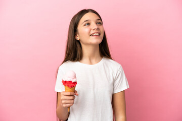 Poster - Little girl with a cornet ice cream over isolated pink background laughing