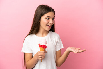 Poster - Little girl with a cornet ice cream over isolated pink background with surprise expression while looking side