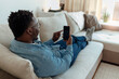 © Jelena Stanojkovic - Shot of a handsome young man using his cellphone while relaxing on the couch at home. Smiling young entrepreneur using mobile phone while sitting on the sofa.