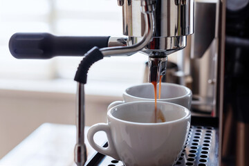 A coffee machine and two white coffee cups.