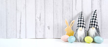 Happy Easter Farmhouse Theme Banner Styled With Small Wood Bunny, Eggs And Buffalo Plaid Gnome Against A White Wood Background. Sized To Fit Popular Social Media And Web Banner.