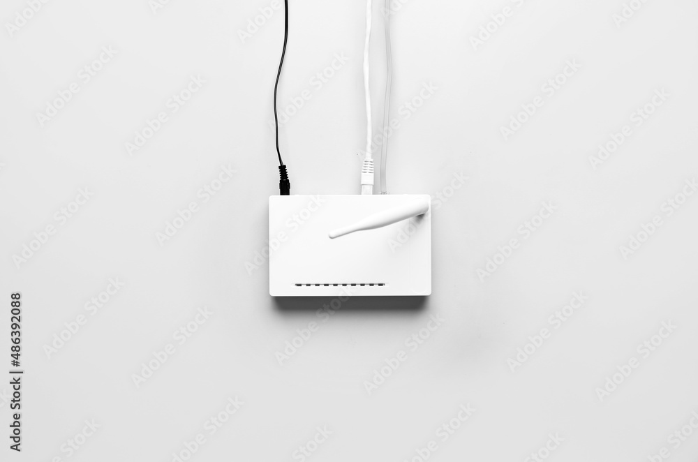 Wi-Fi router with antenna and network cables on light background