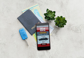 Poster - Mobile phone with open car rent app, passport, key and flowerpots on light background