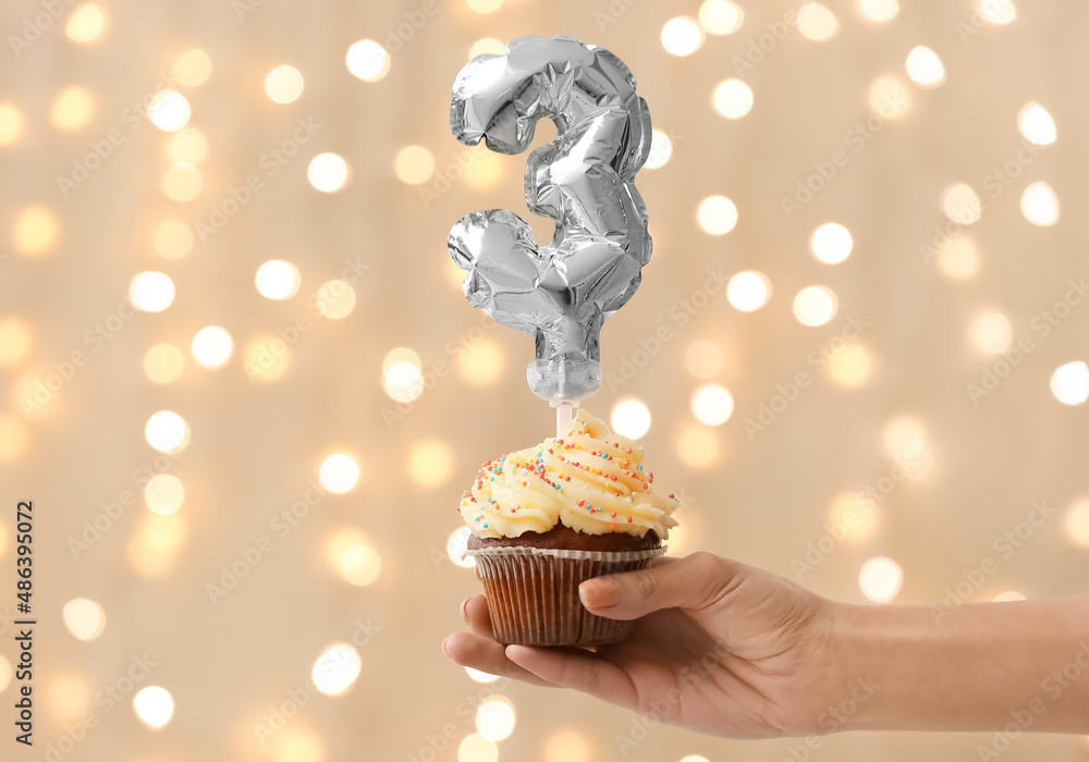 Woman holding Birthday cupcake against blurred background