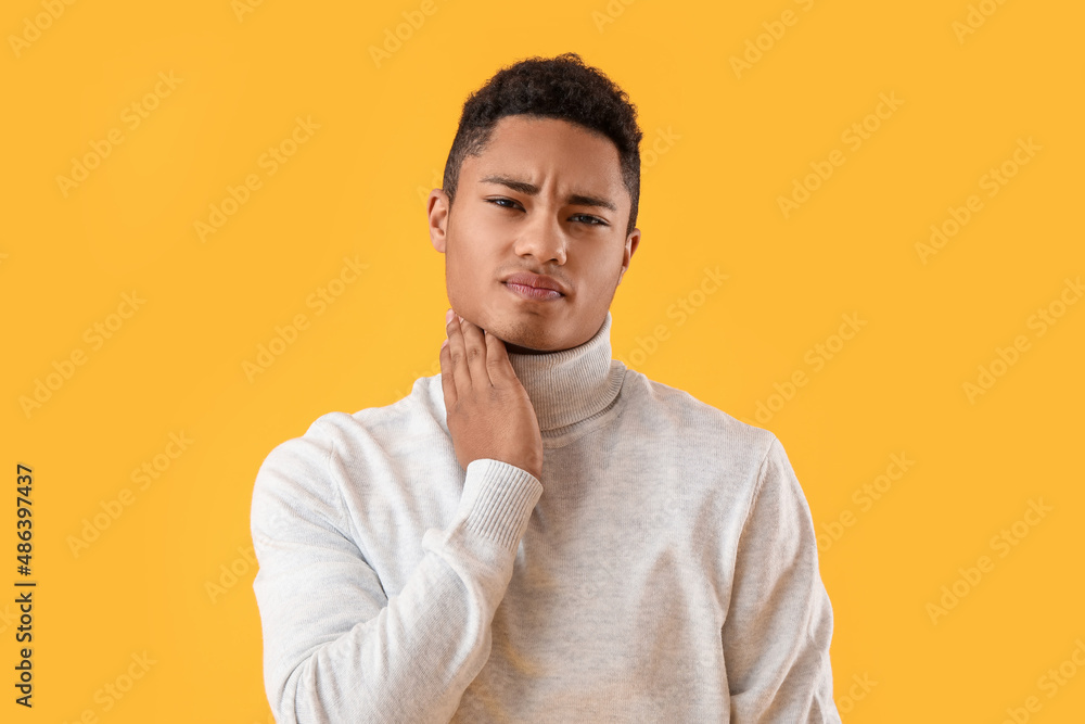 Ill African-American guy with sore throat on color background