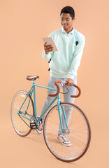 Sticker - Male African-American student with bicycle and tablet computer on color background