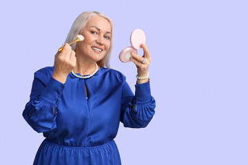 Wall Mural - Mature woman doing makeup on violet background. International Women's Day celebration