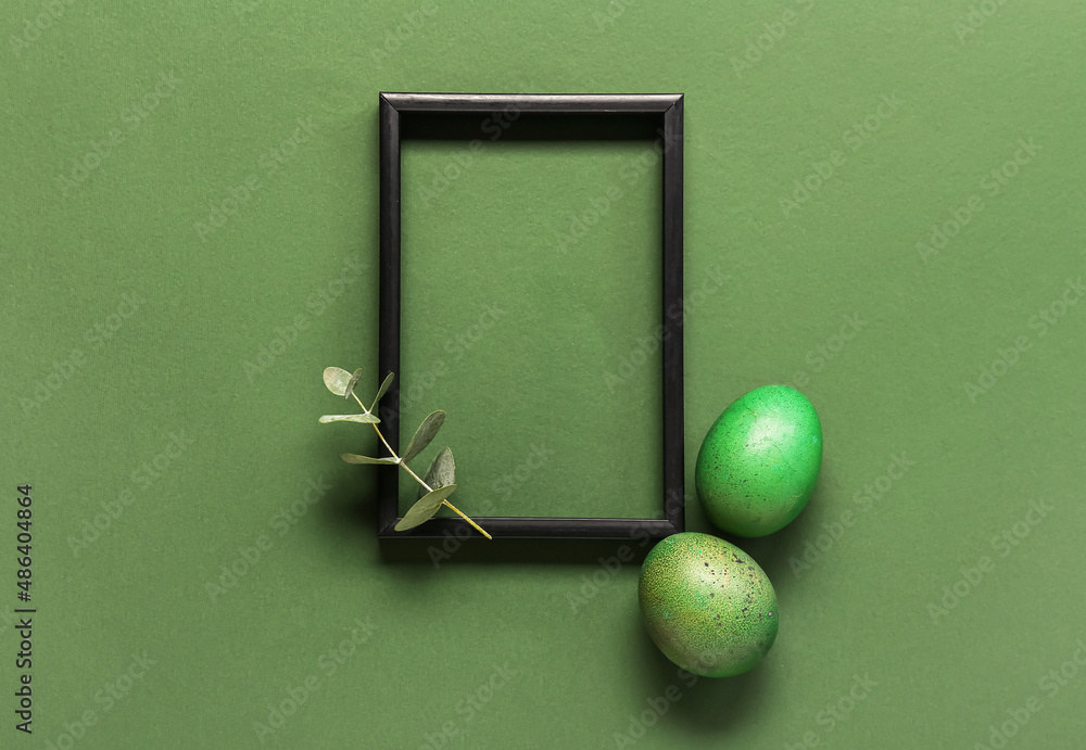 Beautiful composition with frame, Easter eggs and eucalyptus branch on green background