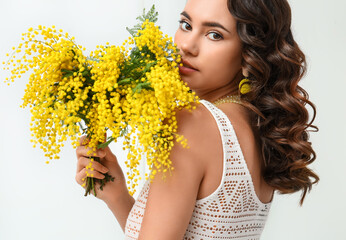 Wall Mural - Beautiful young woman with mimosa flowers on white background