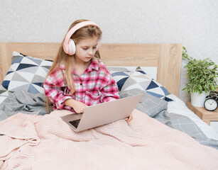 Wall Mural - Little girl learning online with laptop computer at bedroom.