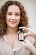 © Parilov - Concept cosmetology against acne. Happy young curly woman holding bottle with beauty skin care product