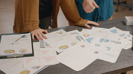 Canvas Print - Close up of colleagues checking papers with data rate charts on table. People using information files to plan business project and presentation, working on startup organization development