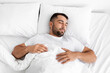 © Prostock-studio - Peaceful calm tired millennial caucasian muscular man lies on white comfortable bed, soft pillow, sleeps alone