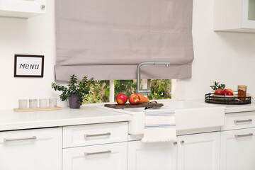 Poster - White kitchen interior with double bowl sink in front of window and fresh fruits