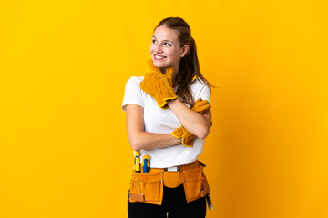 Young electrician woman isolated on yellow background looking to the side