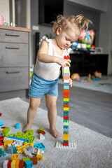 Wall Mural - Caucasian child a little girl is playing in the constructor at home. Educational toys for children.