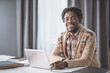 © Svyatoslav Lypynskyy - African American student study from home using laptop sitting next to the window. Young entrepreneur working on his laptop at home. African american student study at home during lockdown