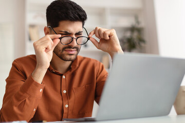 Wall Mural - Confused Arab guy using laptop looking at screen