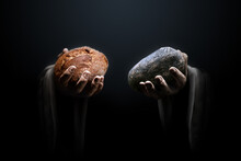 Hands Of A Man Holding A Stone And A Bread. Religious Biblical Theme Concept.