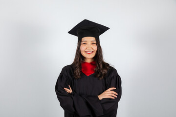 Smiling graduate student in mortarboard and bachelor gown on white background