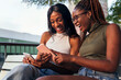 © Raul Mellado - two young women laughing while looking phones