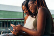 © Raul Mellado - two young women laughing while consulting phones