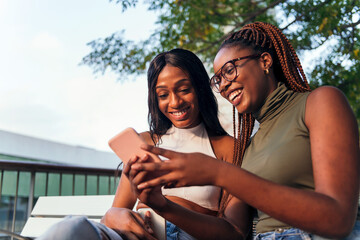 Wall Mural - two young women having fun with a mobile phone