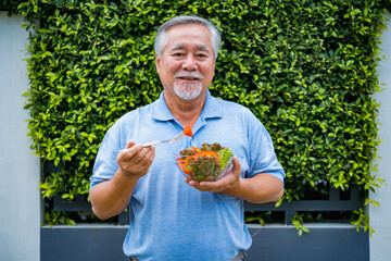 Mature man with healthy food, Portrait Asian Senior man eating a salad in house, Old elderly male health care eat vegetables and useful foods.