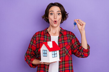 Sticker - Photo of impressed young brunette lady hold house key wear red shirt isolated on purple color background